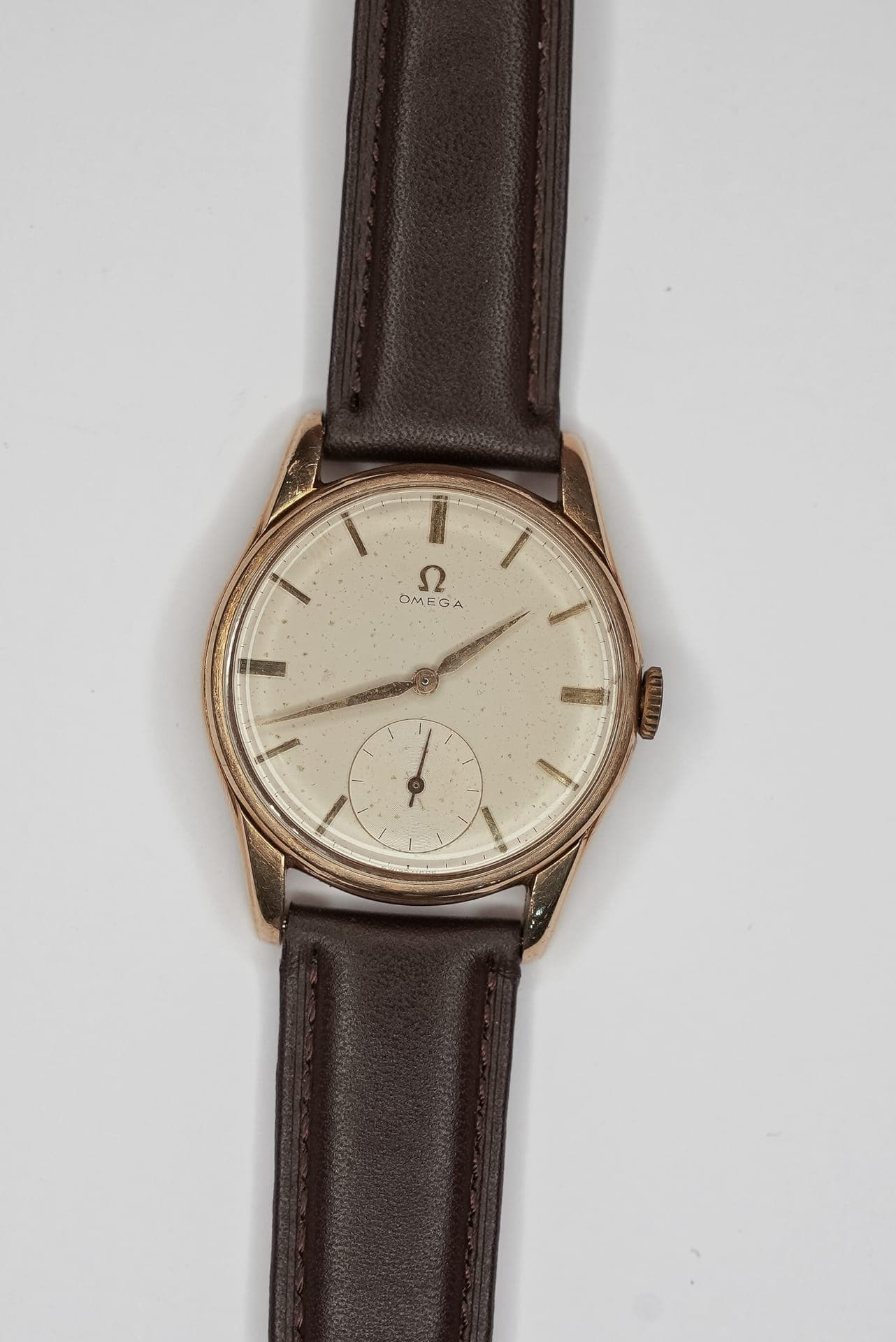 A gold vintage watch on a brown leather strap